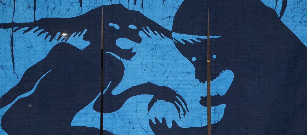 Drei an einer Stange hängende Stoffbahnen bilden zusammen ein Bild. Auf einem blauen Hintergrund sind in dunkelblau zwei Phantasiegestalten abgebildet, die sich gegenüber stehen und miteinander zu kämpfen scheinen.