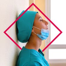 Seitliche Portraitaufnahme einer Frau, die mit geschlossenen Augen an der Wand lehnt. Sie trägt ein türkisefarbenes Oberteil und eine Kopfbedeckung in der gleichen Farbe. Eine OP-Maske ist auf ihr Kinn heruntergezogen.