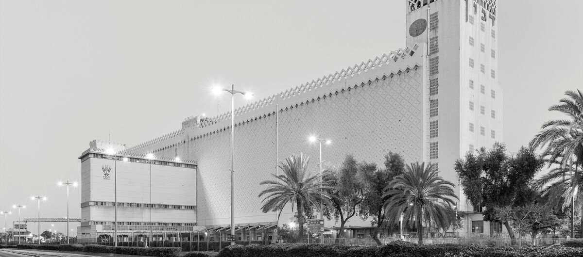Schwarz-weiß Foto vom Ossip Klarwein entworfene Getreidesilo Dagon im Hafen von Haifa. Es ist ein langes hohes schmales helles Gebäude, das auf der rechten Seite mit einem noch etwas höheren Turm abschließt.