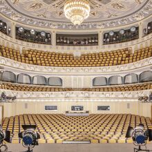 Foto von der Bühne aus in den prachtvollen Zuschauersaal des Staatsschauspiel Dresden. Im Vordergrund stehen auf der Bühne Scheinwerfer, die auf den Saal gerichtet sind. Der Saal ist in Creme- und Goldfarben gehalten.