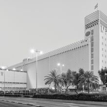 Schwarz-weiß Foto vom Ossip Klarwein entworfene Getreidesilo Dagon im Hafen von Haifa. Es ist ein langes hohes schmales helles Gebäude, das auf der rechten Seite mit einem noch etwas höheren Turm abschließt.