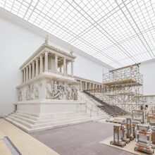 Das Foto zeigt den Pergamonaltar von der linken Seite aus. Mittig auf der hochsteigenden Treppe ist ein Baugerüst aufgebaut. Rechts im Bild lagern Elemente des Altars teil eingepackt.