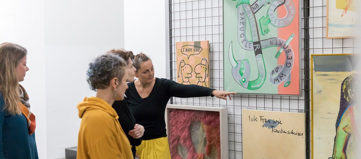 Menschen betrachten verschiedene Bilder mit unterschiedlichen Kunststielen, die eher abstrakt und komisch, als anmutig und schönwirken.