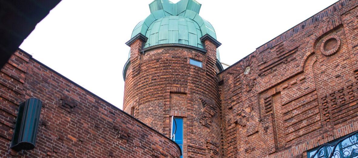 Blick aus der Böttcherstraße auf den Turm des Paula Modersohn-Becker Museums. Der Turm und das Gebäude sind aus rotem Backstein, die Kuppel aus türkisangelaufenen Kupfer.