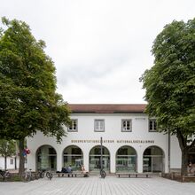 Foto der Außenansicht des Dokumentationszentrums Nationalsozialismus der Museen Freiburg. Fünf Rundbögen mit Fensterglas prägen die Hausfront im Erdgeschoss. Darüber ist der Schriftzug Dokumentationszentrum Nationalsozialismus zu lesen.